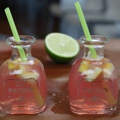 two glass bottles filled with lemonade next to a lime