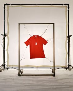 a t - shirt is hanging in front of a photo frame with clothes on it