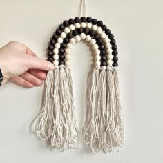 a person is holding some beads and tassels in their hand while they are hanging on the wall