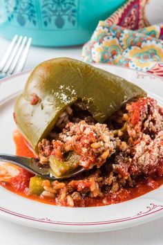 a white plate topped with stuffed peppers covered in sauce