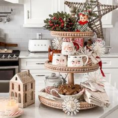 a three tiered tray filled with coffee mugs and cookies on top of a kitchen counter