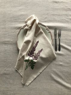 a table setting with napkins, fork and knife on top of the table cloth