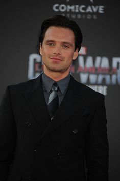 a man in a black suit and tie posing for the camera at a red carpet event