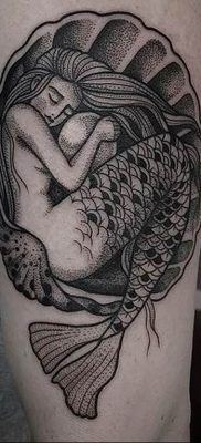 a black and white photo of a woman with a fish tattoo on her thigh,