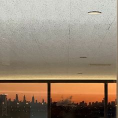 the view from an office building at sunset with rain drops on the window panes