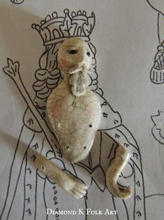 an old doll with a crown on it's head and a stick in its mouth