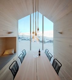 a long table with four chairs in front of a window that looks out onto the snow covered mountains