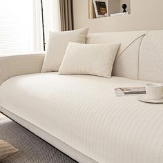 a white couch with pillows and a cup on it