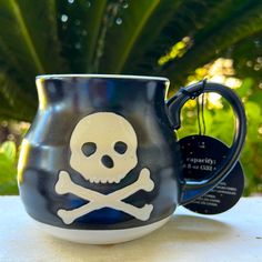 a skull and crossbones mug is sitting on a table next to a plant