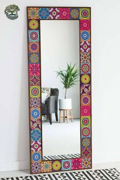 a large mirror sitting on top of a floor next to a potted palm tree