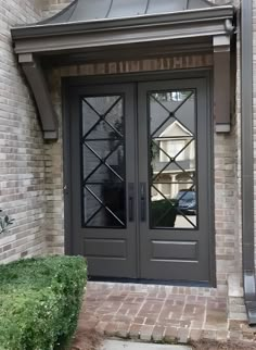 the front door to a home with two glass doors and brick walkway leading up to it