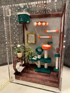 a display case with various cat toys in it's glass front door, and a potted plant on the other side