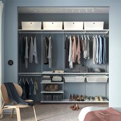 an organized closet with clothes and shoes on the shelves, in front of a bed