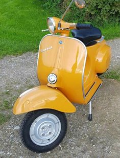 a yellow scooter is parked on the gravel