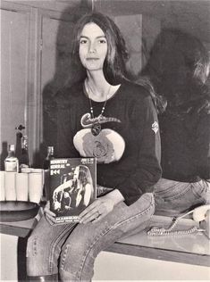 black and white photograph of woman sitting on counter with book