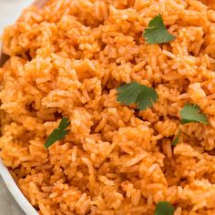 a white bowl filled with rice and garnished with cilantro on top