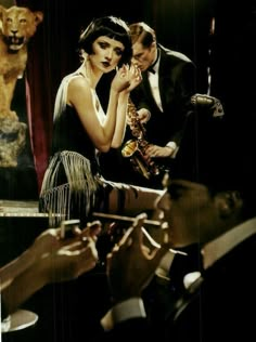 a woman in a black dress is holding a saxophone while two men are standing behind her