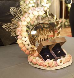 a table with an open ring box on top of it and flowers in the middle