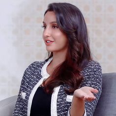 a woman sitting on top of a couch holding her hand out to the side with one hand