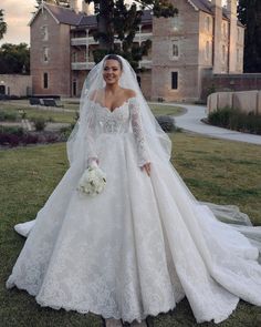 a woman in a wedding dress standing on the grass with her veil over her head