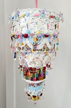 a cake with many different decorations hanging from it's side on a stand in front of a white wall