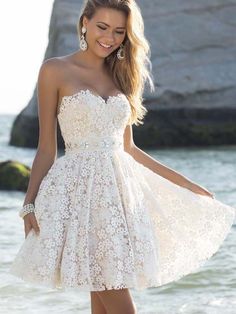 a woman in a short white dress standing on the beach