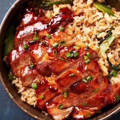 a bowl filled with rice and meat covered in sauces, green onions and scallions