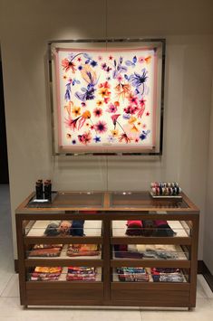 a display case in front of a painting with flowers on it and other items underneath