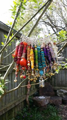 a bunch of bracelets hanging from a tree in a yard with rocks and trees