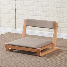 a wooden chair sitting on top of a carpeted floor next to a white brick wall