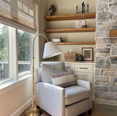 a living room with stone fireplace and built in shelves on either side of the window