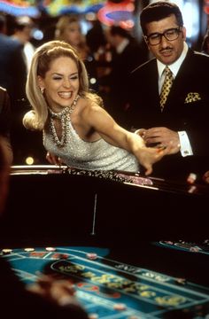 a man and woman are playing roulege in a casino room with other people