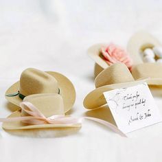 two hats and a note sitting on a table with ribbons attached to the hat's brims