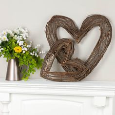 a heart shaped sculpture sitting on top of a mantle next to a vase with flowers