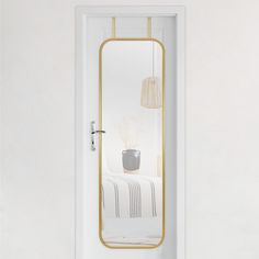 a white door with a mirror reflecting a bed and lamp on the wall next to it