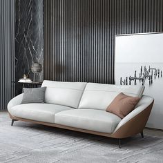 a white leather couch sitting in front of a wall with black and brown stripes on it