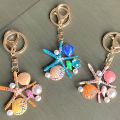 three seashells and starfish key chains on a table