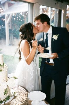 a bride and groom are kissing in front of a wedding cake as they eat it