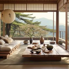 a living room filled with furniture next to a window covered in trees and mountains on the other side