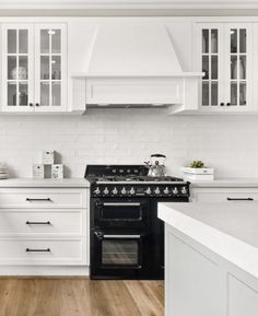 a black stove top oven sitting inside of a kitchen next to white cabinets and drawers