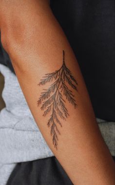 a woman's arm with a tattoo on it that has some branches growing out of it