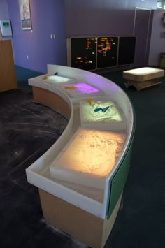 a curved display case in an office with colorful lights on the walls and below it