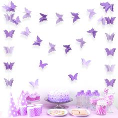 a table topped with cake and cupcakes covered in purple butterflies