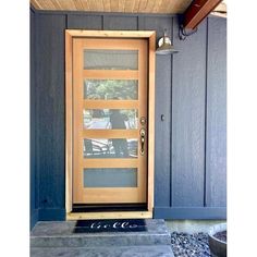 a wooden door with glass on the side of a house in front of a blue wall