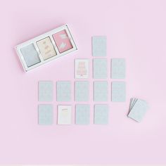 a pink and white box with some cards next to it on a pink table top