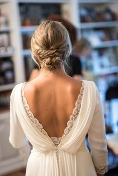 the back of a woman's wedding dress in front of a shelf full of books