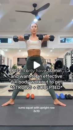 a woman is doing exercises with dumbbells in front of a ceiling mounted fan