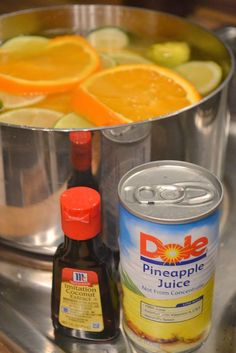 oranges, limes and juice are in a pot on the stove top next to a can of dole pineapple juice