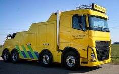 a yellow truck is parked on the side of the road in front of some grass