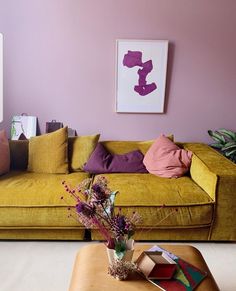 a living room with yellow couches and pink walls in the corner, including a coffee table